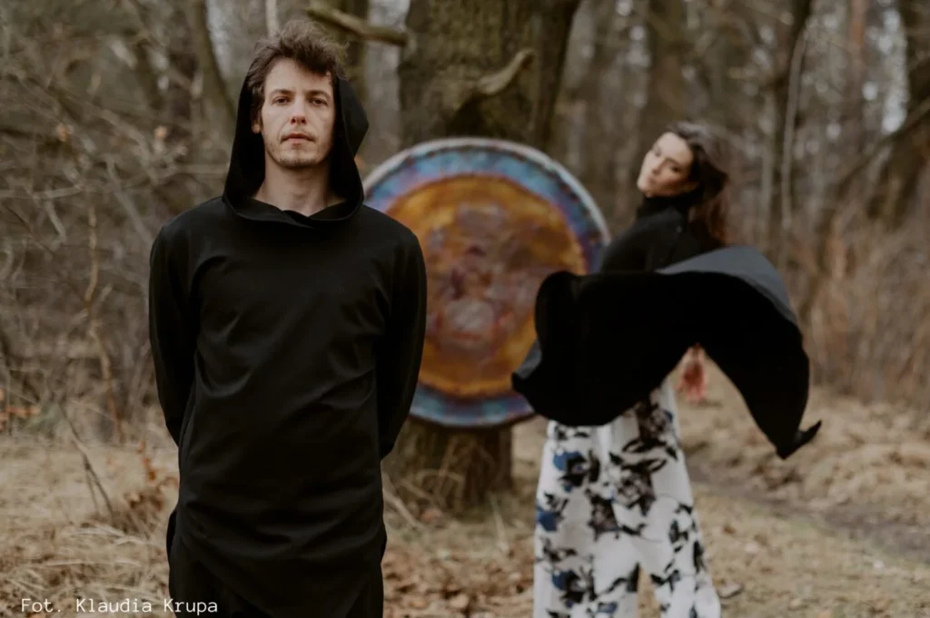 Life as an Artist in Poland: A man standing in the forest, with a woman dancing behind him