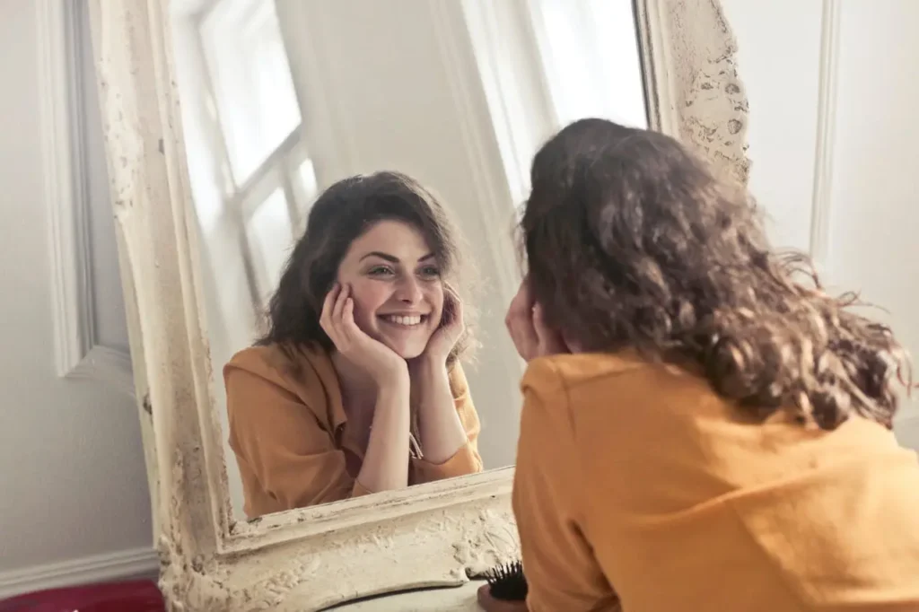 Body Positivity for the Poor. Beauty for the Rich: A woman smiling at herself in the mirror