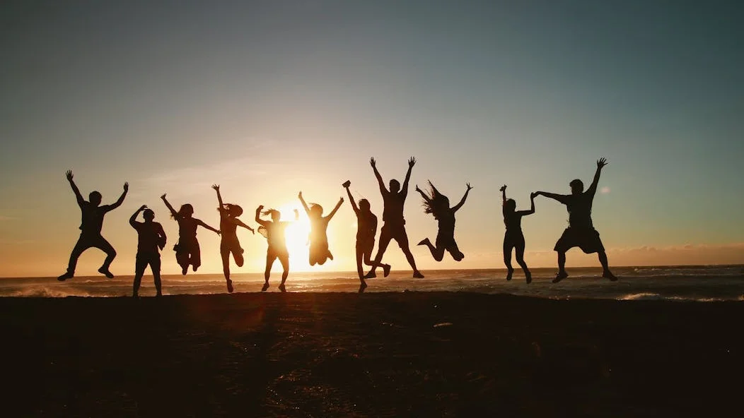 People jumping joyfully against the backdrop of a sunset