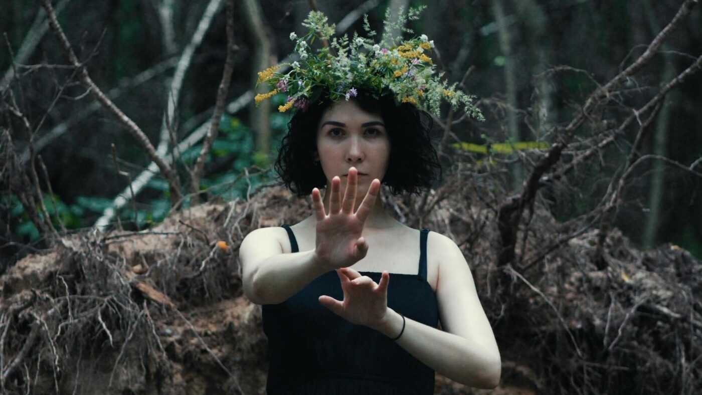 Decline of Christianity: A woman standing in the forest with a wreath on her head and an outstretched hand