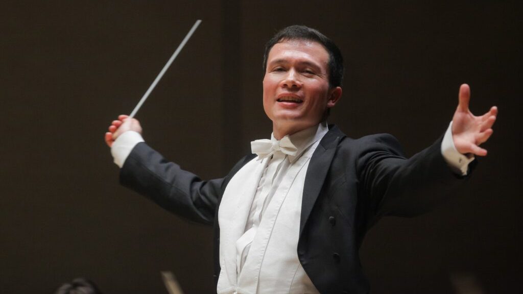 Cavatina Philharmonic Orchestra: The conductor Stanley Dodds enthusiastically leads the orchestra, captured mid-gesture with a baton in hand.