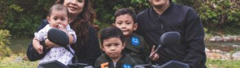 Misconceptions about Large Families: A family with three young children sitting and standing around and on a quad bike