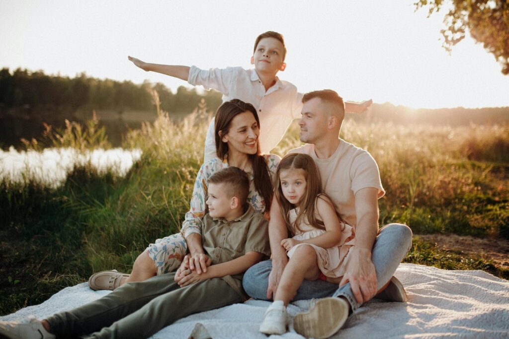 Misconceptions about large families: A happy family with 3 children sitting on a blanket in a meadow