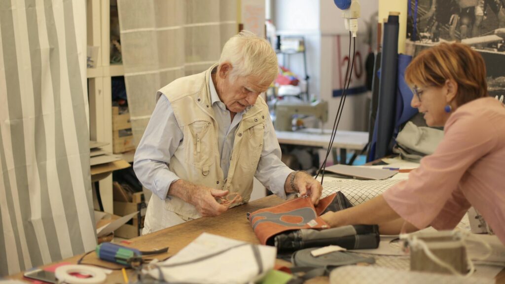 Modern craftsmanship: an old man with gray hair is making a leather bag in a leather workshop