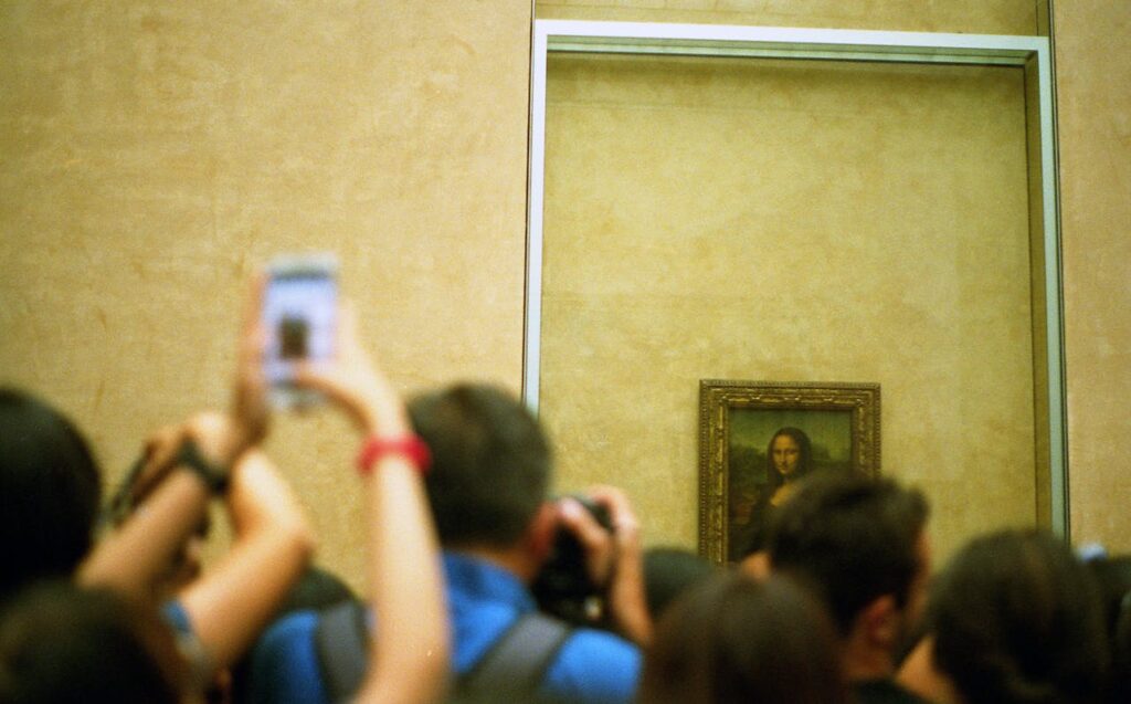 A crowd of people watching and taking photos of the Mona Lisa painting