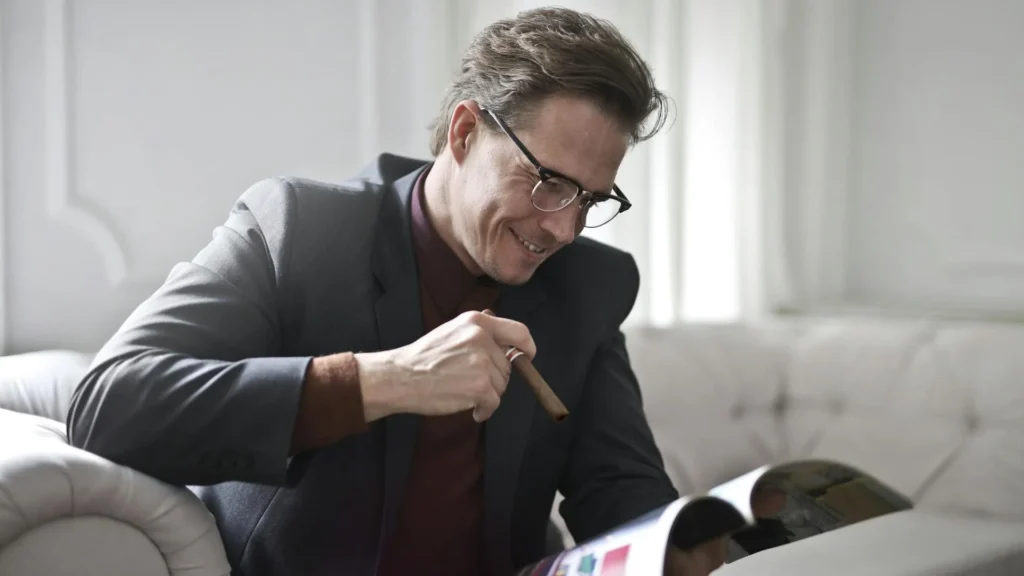 A wealthy man with a cigar reading through a catalog