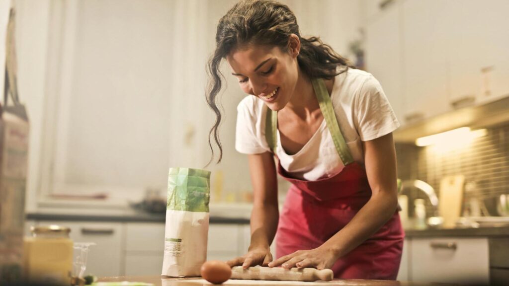 Rise of the Trad Wife: A happy young woman is rolling the dough