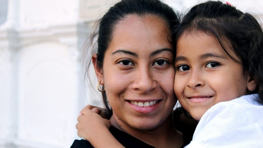 Feminism and Motherhood: A mother and daughter smile warmly as they embrace, highlighting their close bond and affection.