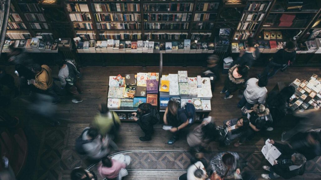 Modern Bestsellers: A busy bookstore with people browsing at tables full of books, seen from above, creating a dynamic and lively atmosphere.