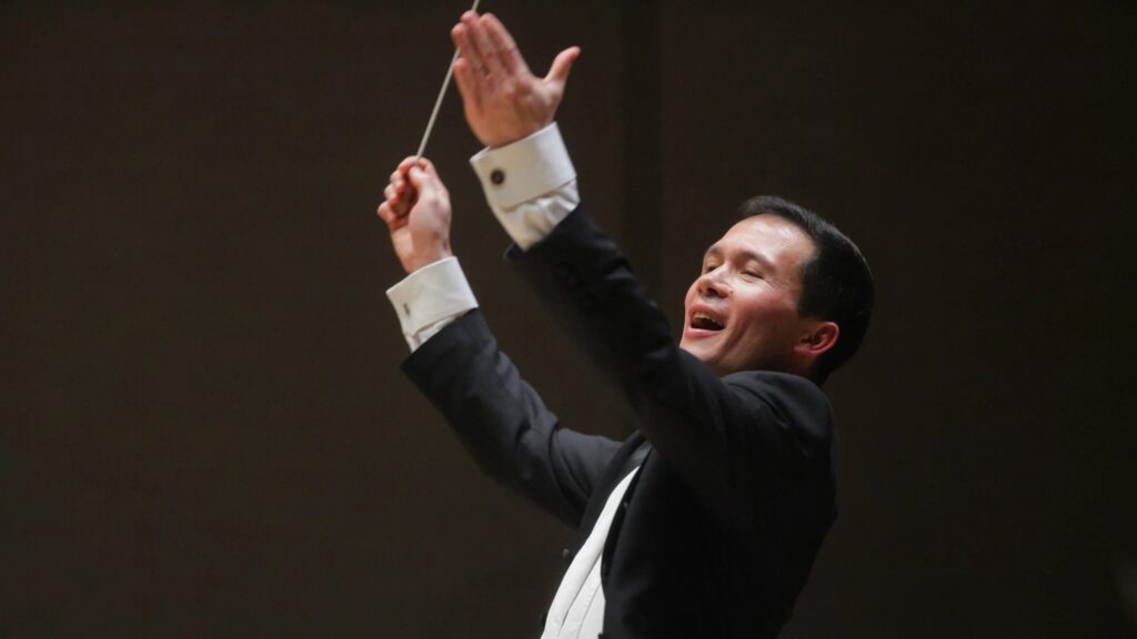 Private Orchestra in Poland: The conductor Stanley Dodds energetically leads the orchestra, captured mid-motion with a baton in hand and a joyful expression.