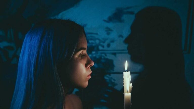 Blackout reactions: A young woman looking at a candle flame.
