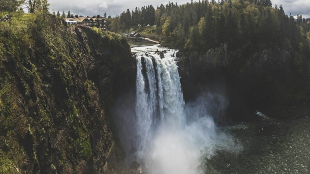 The Disenchanted World: A wide view of Snoqualmie Falls in Washington, with the Salish Lodge above—the iconic Twin Peaks waterfall from the TV series.