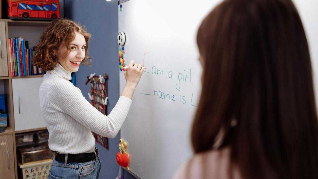 How to Wisely Praise a Child: A female teacher at the whiteboard smiles at a student.
Fot. Thirdman / Pexels