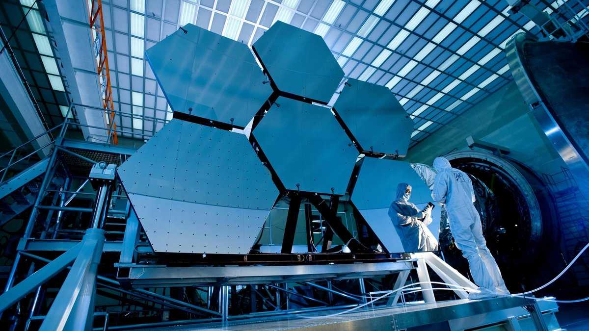 The world's largest telescope. Photo: Pixabay/pexels. Scientists in jumpsuits work on a segmented telescope mirror in a laboratory.