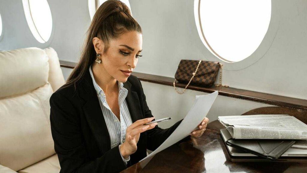 The Psychology of Wealth: Woman reads documents on an airplane