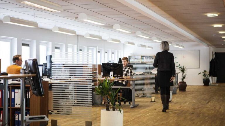 AI in a company A modern open-space office with employees working on computers.