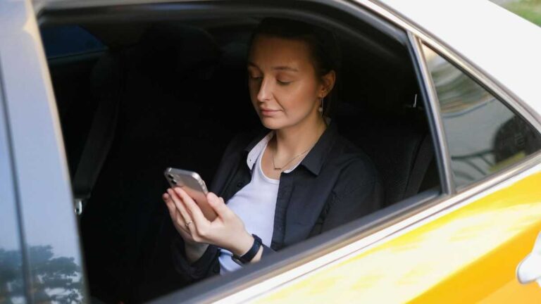 Bolt drivers recording passengers. A woman is sitting in a car and looking at her phone. Fot. Anna Shvets / Pexels