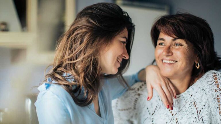 Human Aging Process: A young woman rests her hand on the shoulder of her older friend.