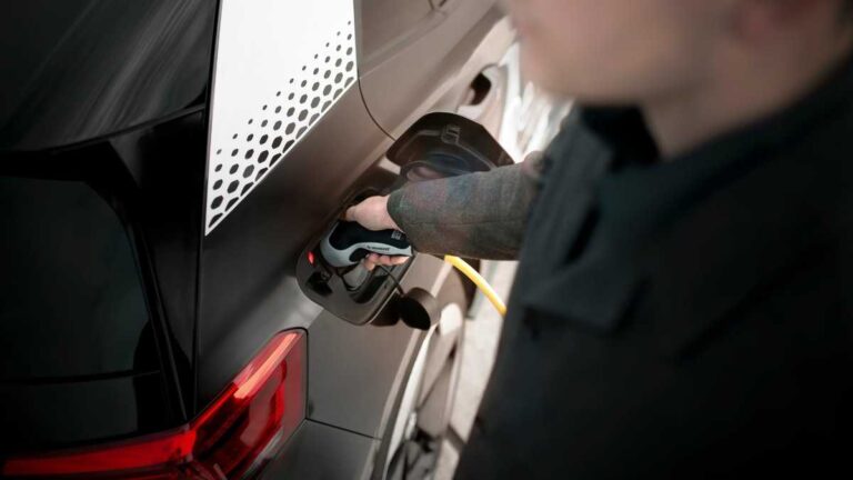 New water-based battery: A man charges an electric car with a power cable.