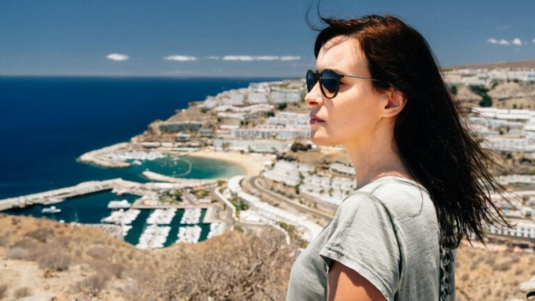 The compulsion to travel: a woman in a gray T-shirt on a hill.