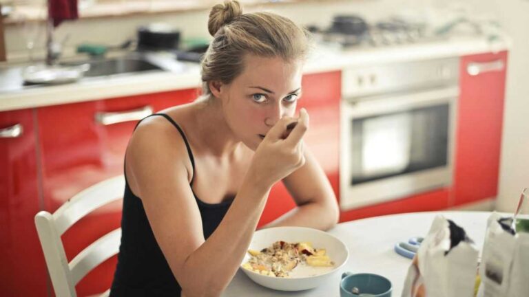 Processed food and weight loss. A woman in a black T-shirt is eating oatmeal.