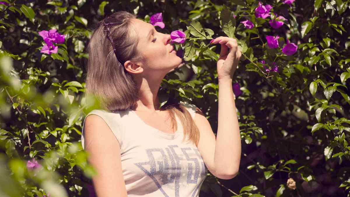 How to restore smell: a woman smells flowers in a garden. Photo by Atlantic Ambience / Pexels