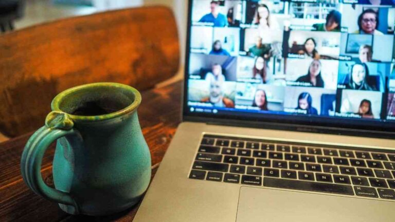 Remote work consequences: A coffee mug next to a laptop with a video call on the screen. Photo: Chris Montgomery / Unsplash