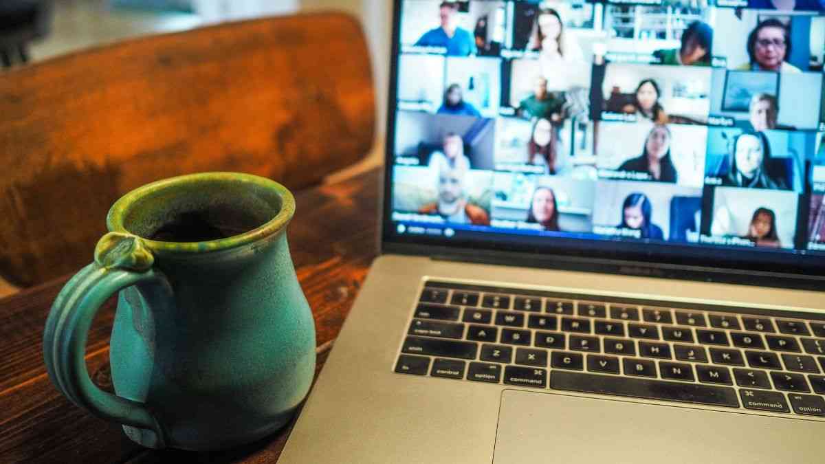 Remote work consequences: A coffee mug next to a laptop with a video call on the screen. Photo: Chris Montgomery / Unsplash