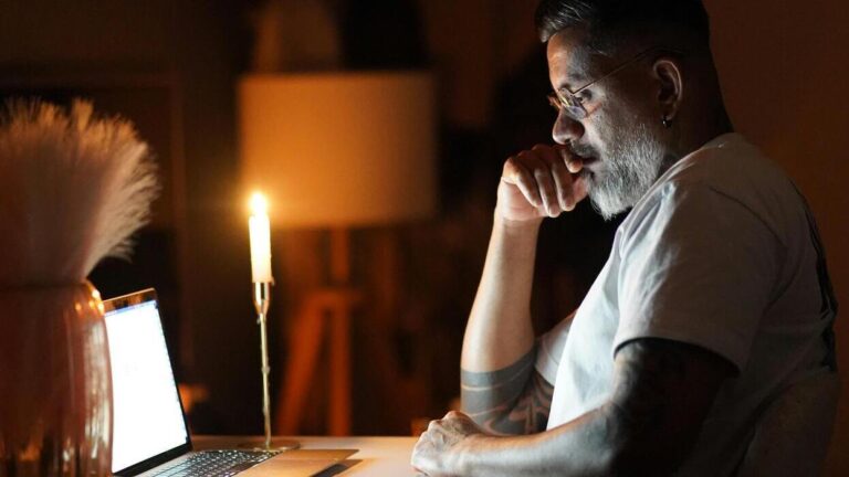 AI Spirituality Meets the Human Soul. A striking night scene: A man sits focused on his laptop, illuminated solely by candlelight. This image powerfully captures the tension between the cold glow of technology and the warm light of human introspection, a divide increasingly bridged by AI spirituality and sense of purpose. Credit: Yasintha Dinuk/Pexels