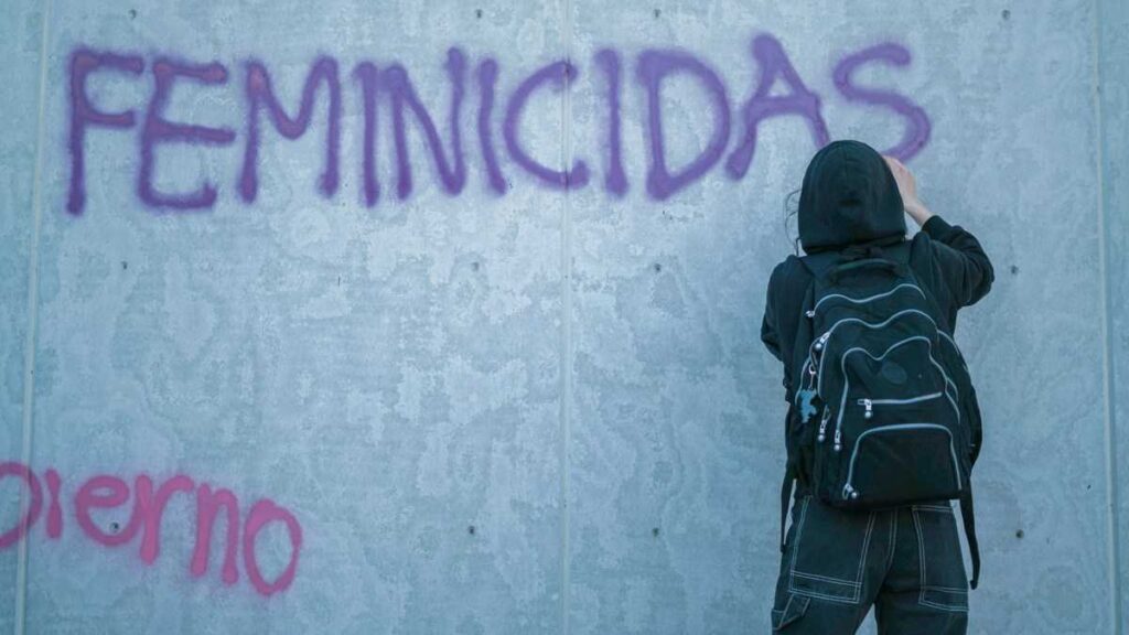 Latin America Femicide: Woman writing with spray paint on a wall.