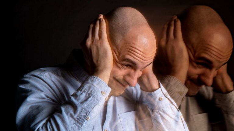 Diagnosis of schizophrenia: man covering his ears, illustrating auditory hallucinations.