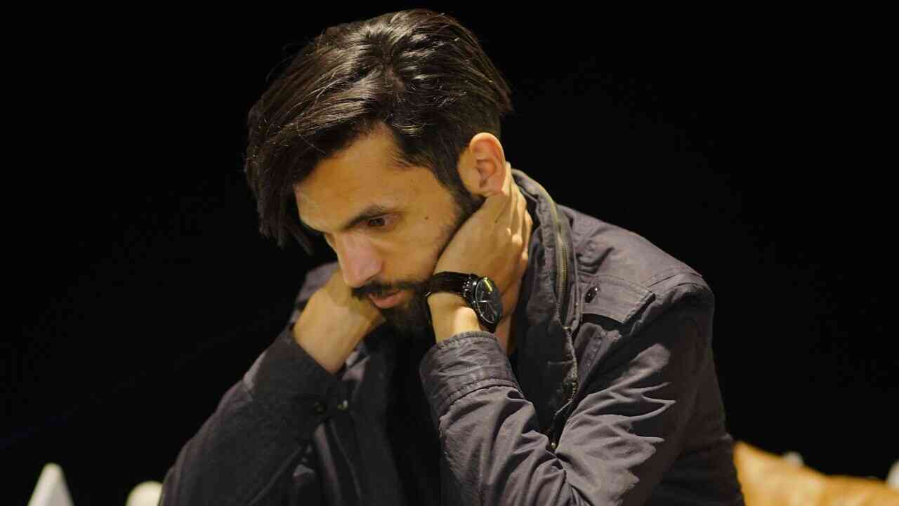 A man bent forward, hands on the back of his neck in tension — an illustration of self-sabotage in practice and the question of why we sabotage ourselves.