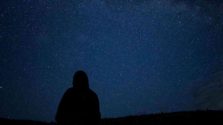 A human silhouette against a night sky filled with stars—a reflection on the nature of time and its perception.