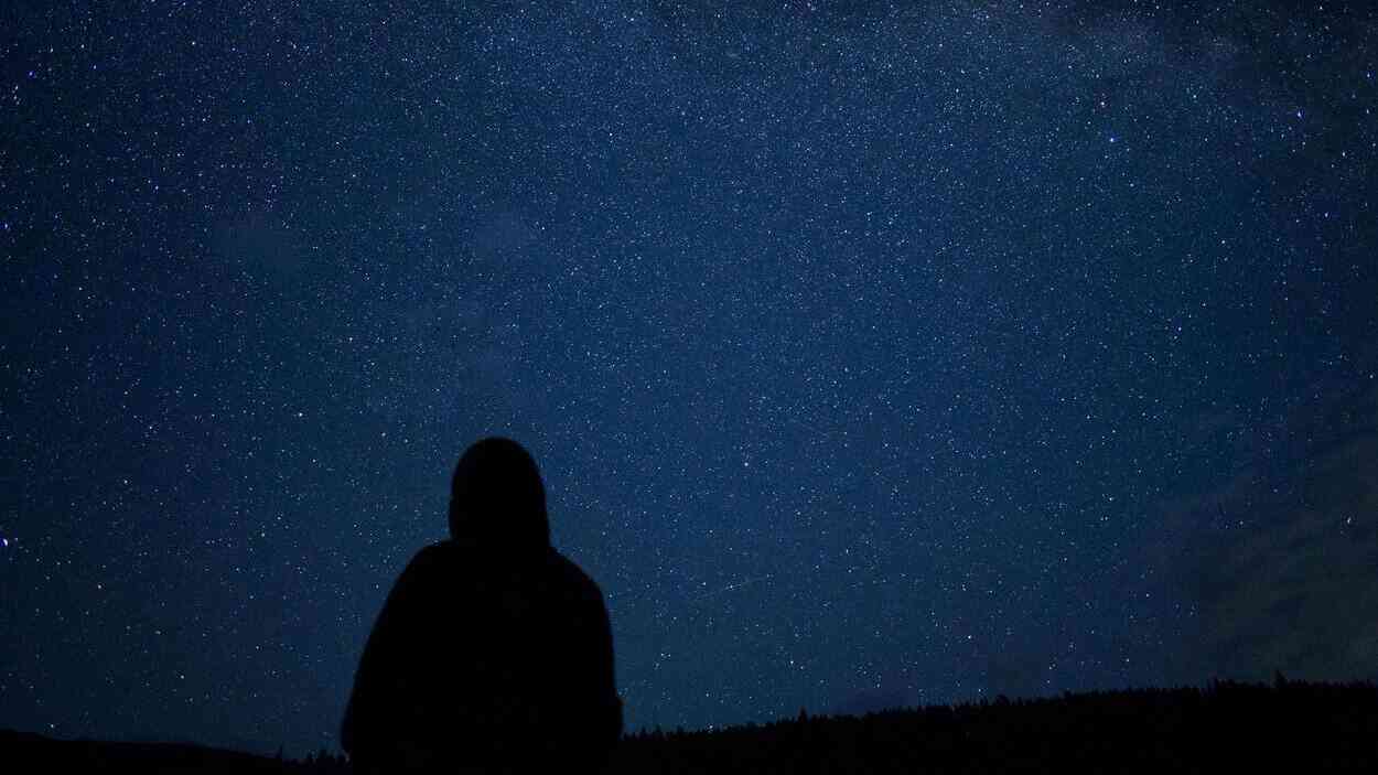 A human silhouette against a night sky filled with stars—a reflection on the nature of time and its perception.