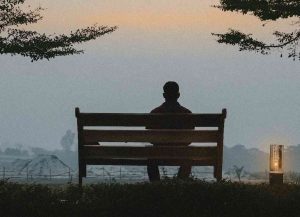 A lonely man sits on a bench in a park at dusk, surrounded by silence and deep in thought. He reflects on life, fear, and hope.
