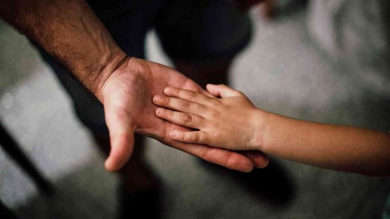 a man and a child touch hands