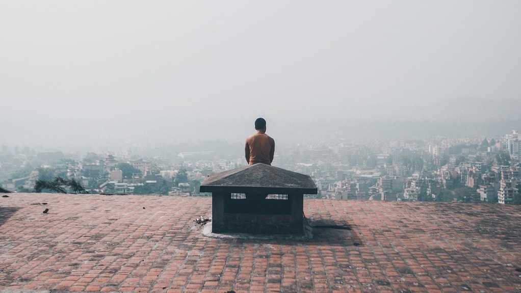 The twilight of humanism: a solitary man gazes at the city in the background.