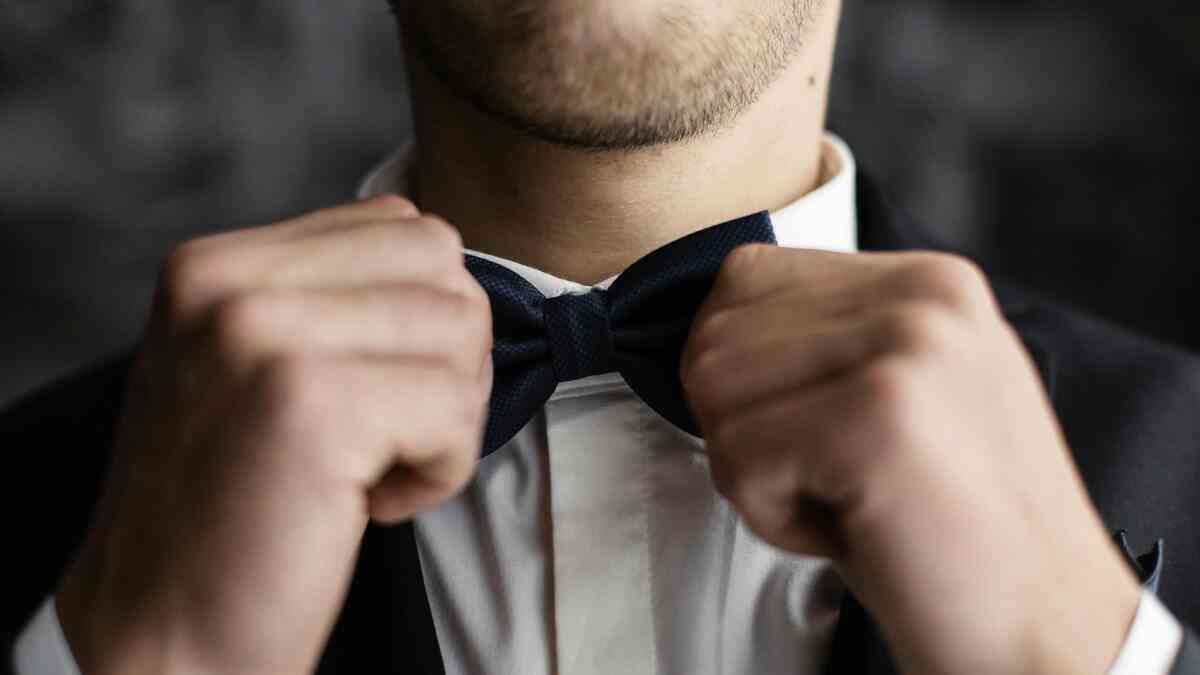 A man adjusts his bow tie in a tuxedo, wondering what the future of James Bond will be.