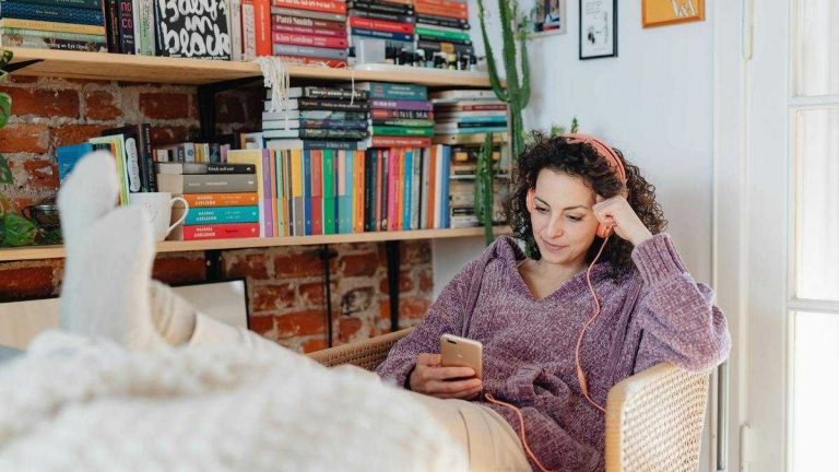 Audiobooks: a woman wearing headphones sits in an armchair with her feet resting on the table