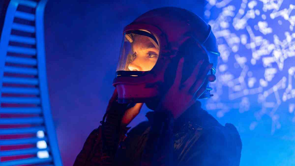 A woman in a helmet, set against a futuristic backdrop, makes contact with an alien civilization.