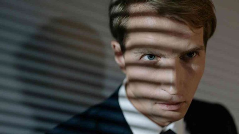 The face of a man in a suit casting a shadow, suggesting the relationship between personality and career choice.