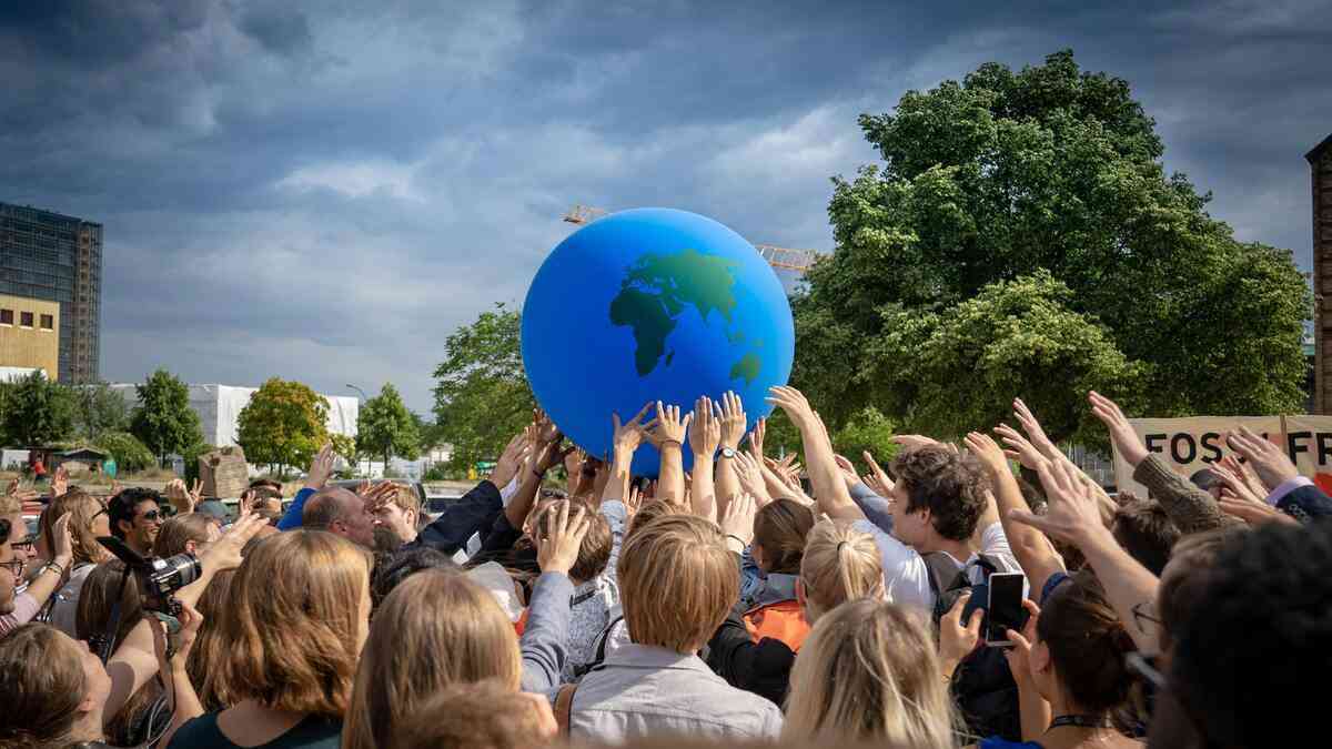 What can save the planet? A crowd reaches out toward the globe. A new force of nature — collective human agency.