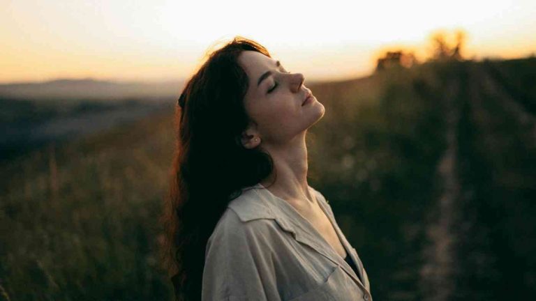 A woman standing in a field at sunset