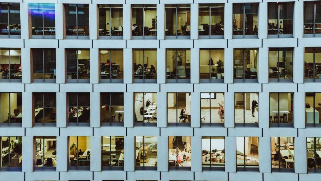 Stoic lifestyle: the façade of an office building, with life in motion behind rows of windows as people work
