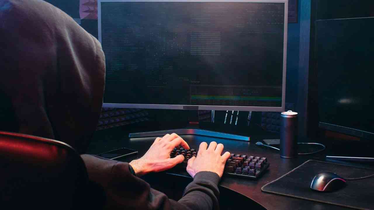The image shows a man in a black hoodie working at a computer on AI in politics.