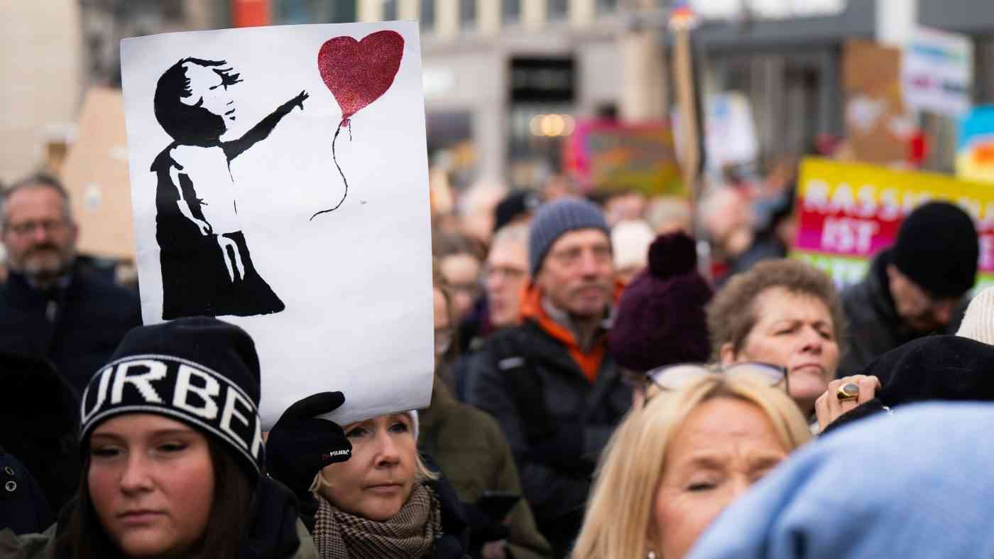 Protesters holding a poster of a child with a heart symbolise a call for compassion in politics.