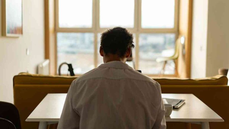 A lonely, sad man working from home, experiencing the subtle downsides of remote work.