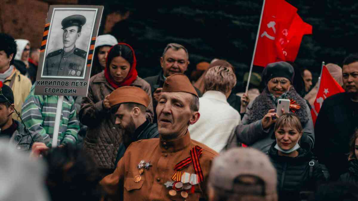 A man in uniform against a backdrop of communist flags, surrounded by people wondering whether communism is coming back.