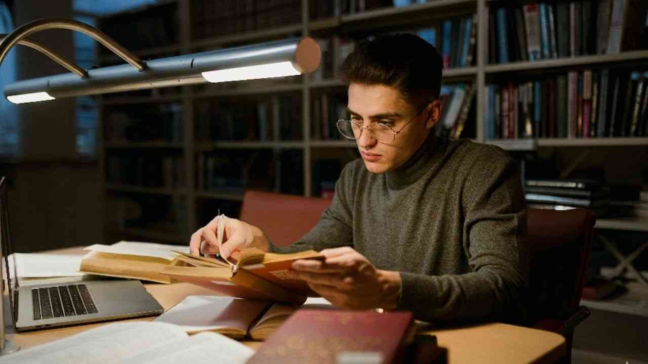 A tired young man sits at a desk, studying.