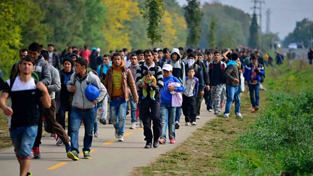 Illustrative photo for EU migration policy. Migrants walk in a crowd along a road toward Europe. This could reflect the consequences of adopting the EU Migration Pact.